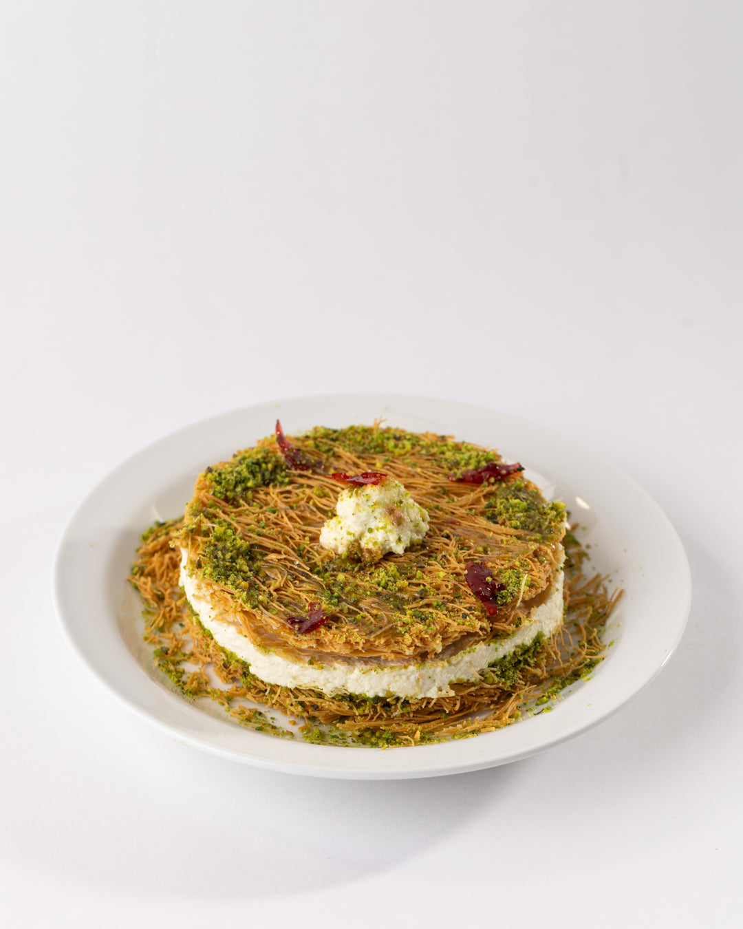 Traditional Esmaliye Plate with vermicelli dough, kashta filling, pistachio paste, and garnished with nuts on white plate