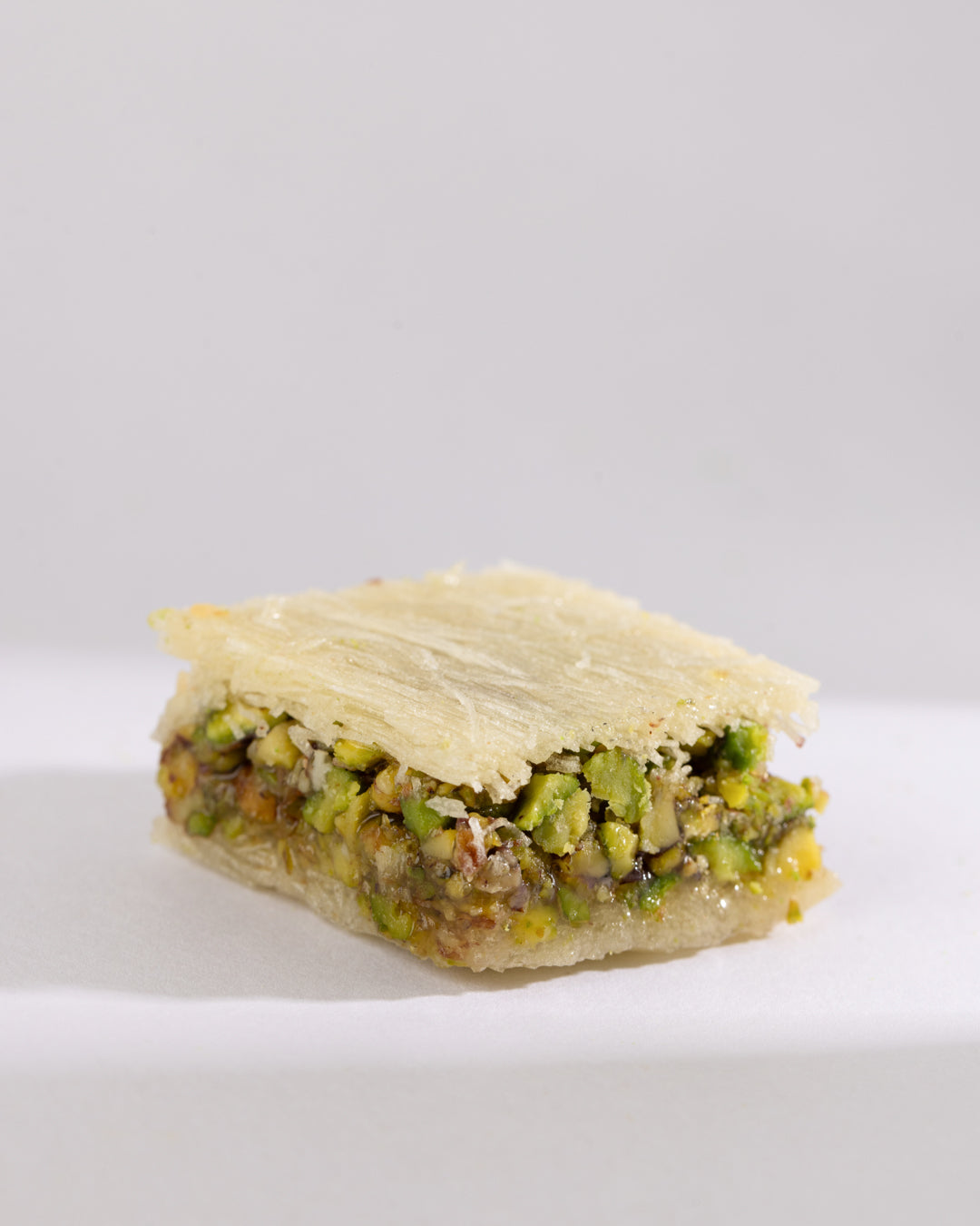 Square ballouriye pastry filled with crushed pistachios and sweet syrup in vermicelli dough layers