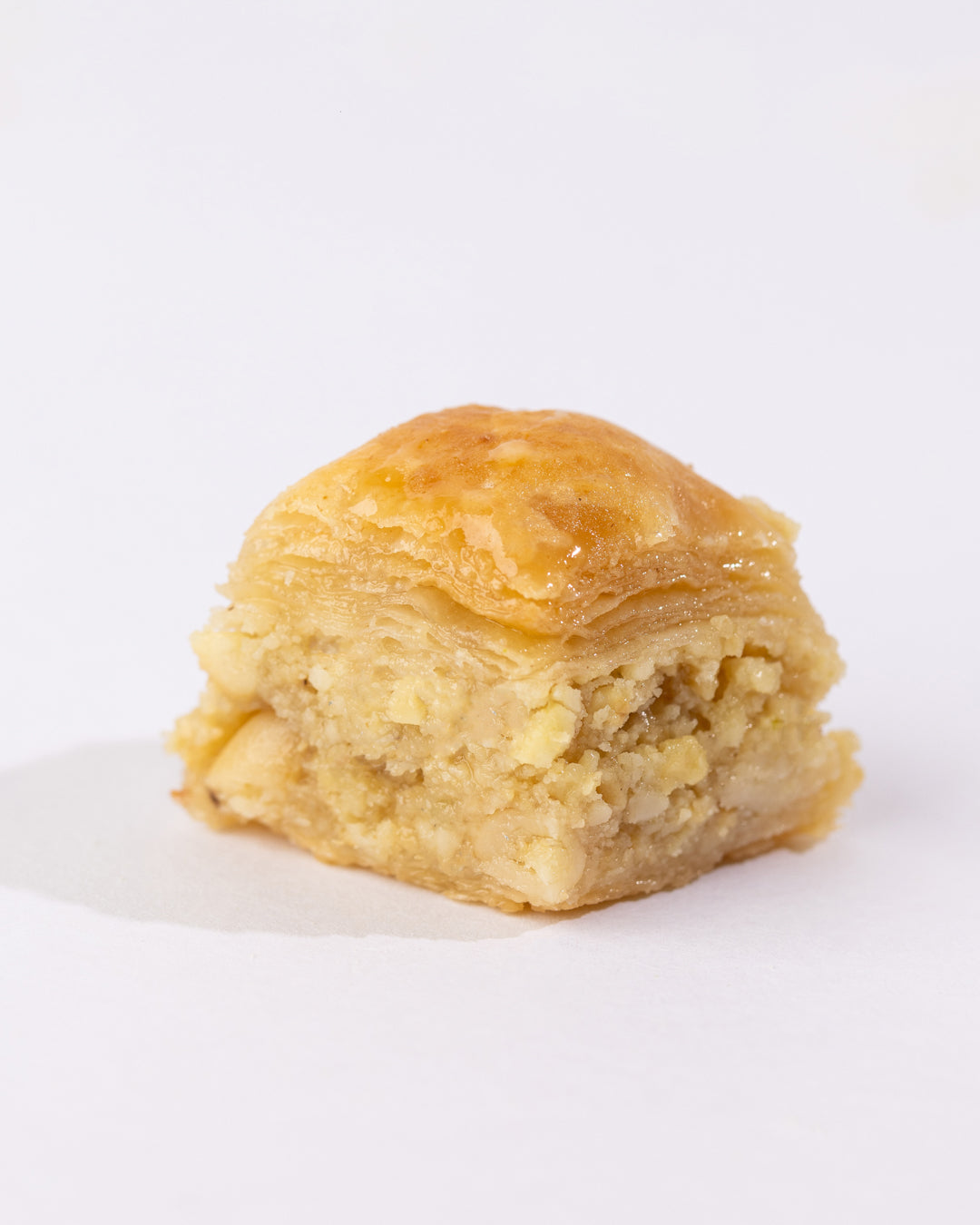 Close-up of a single Beklewa BL Cashew puff pastry crisp filled with crushed cashews and syrup glaze on top.