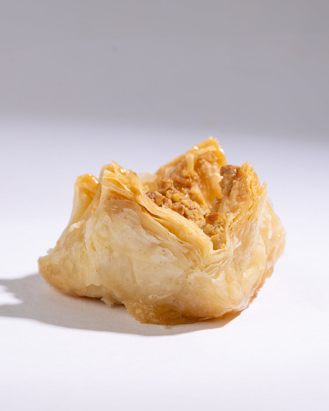Close-up of a flaky pastry filled with crunchy Bokaj cashew nuts on a plain white background