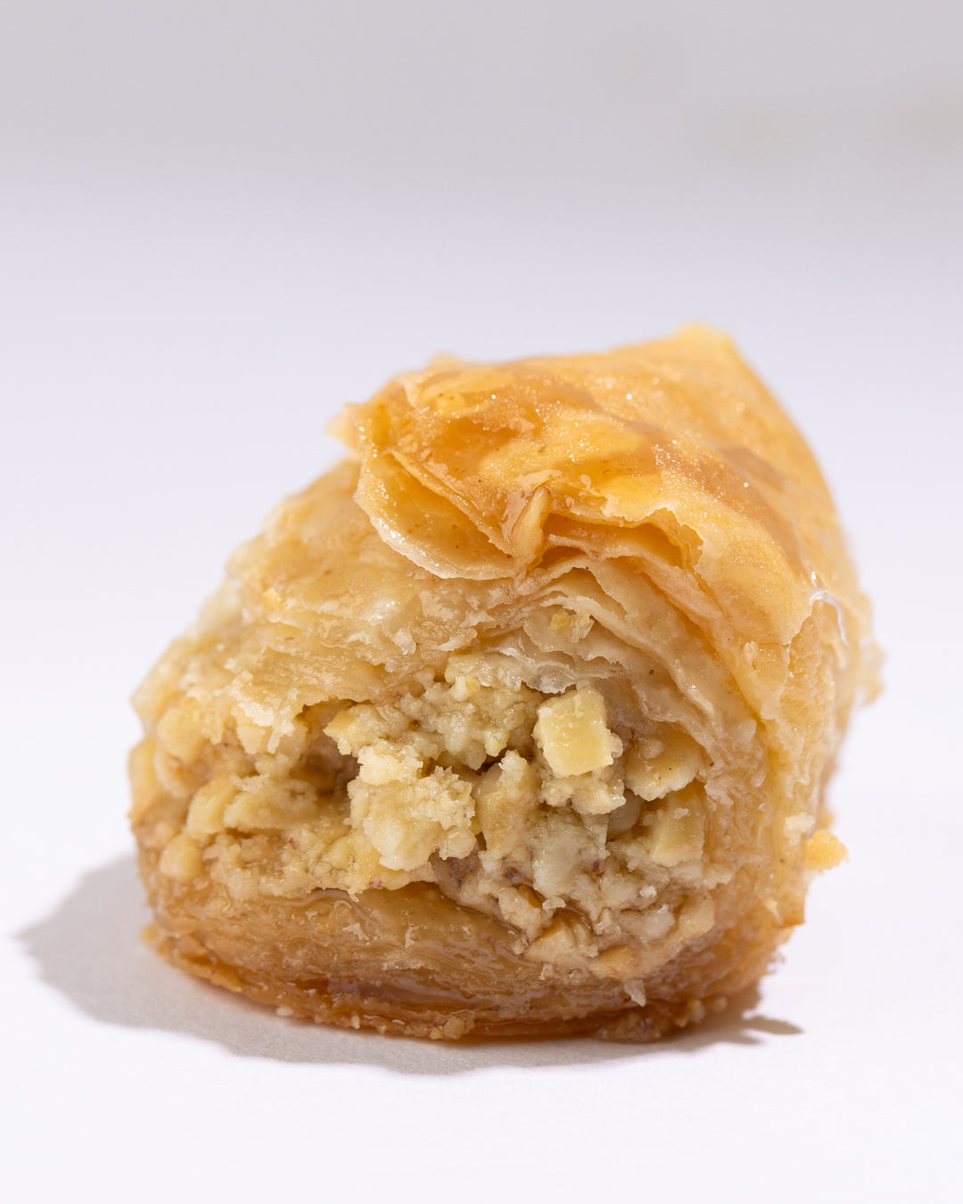 Close-up of Kol w shkor cashew pastry showing flaky puff layers and a rich cashew nut filling.