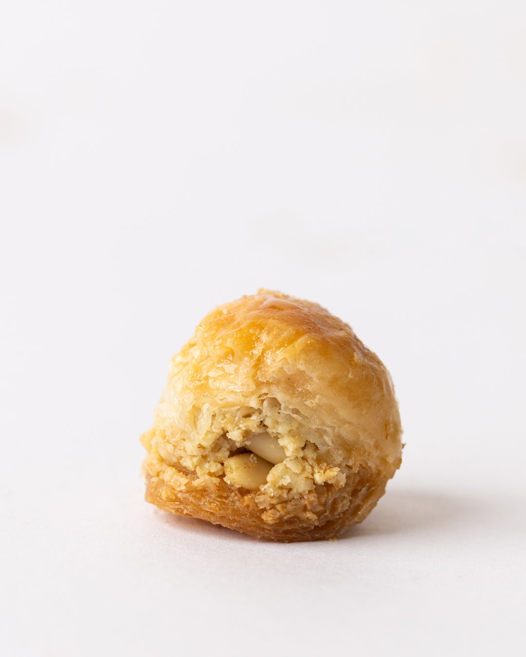 Golden puff pastry crisp filled with pine nuts and coated in sweet sugar syrup on white background