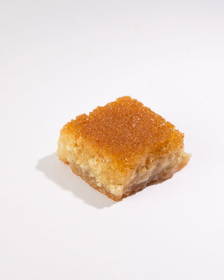 Square piece of Maamoul Mad Walnuts with golden semolina dough and rich walnut filling on white background