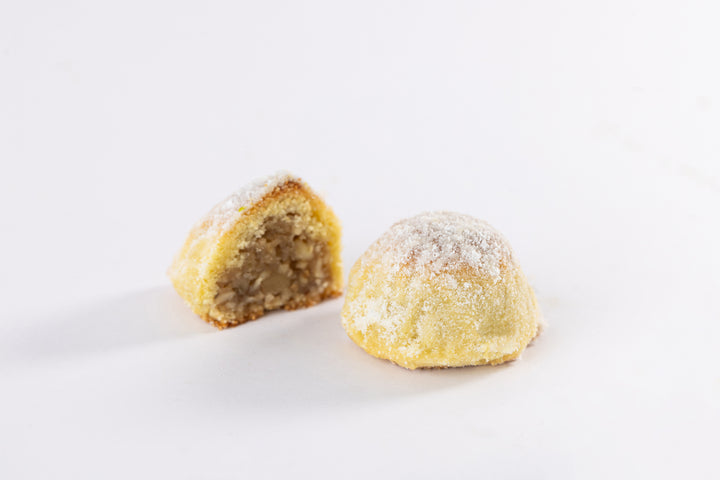 Traditional Maamoul Walnuts pastry dusted with powdered sugar, showcasing a walnut-filled center on a white background