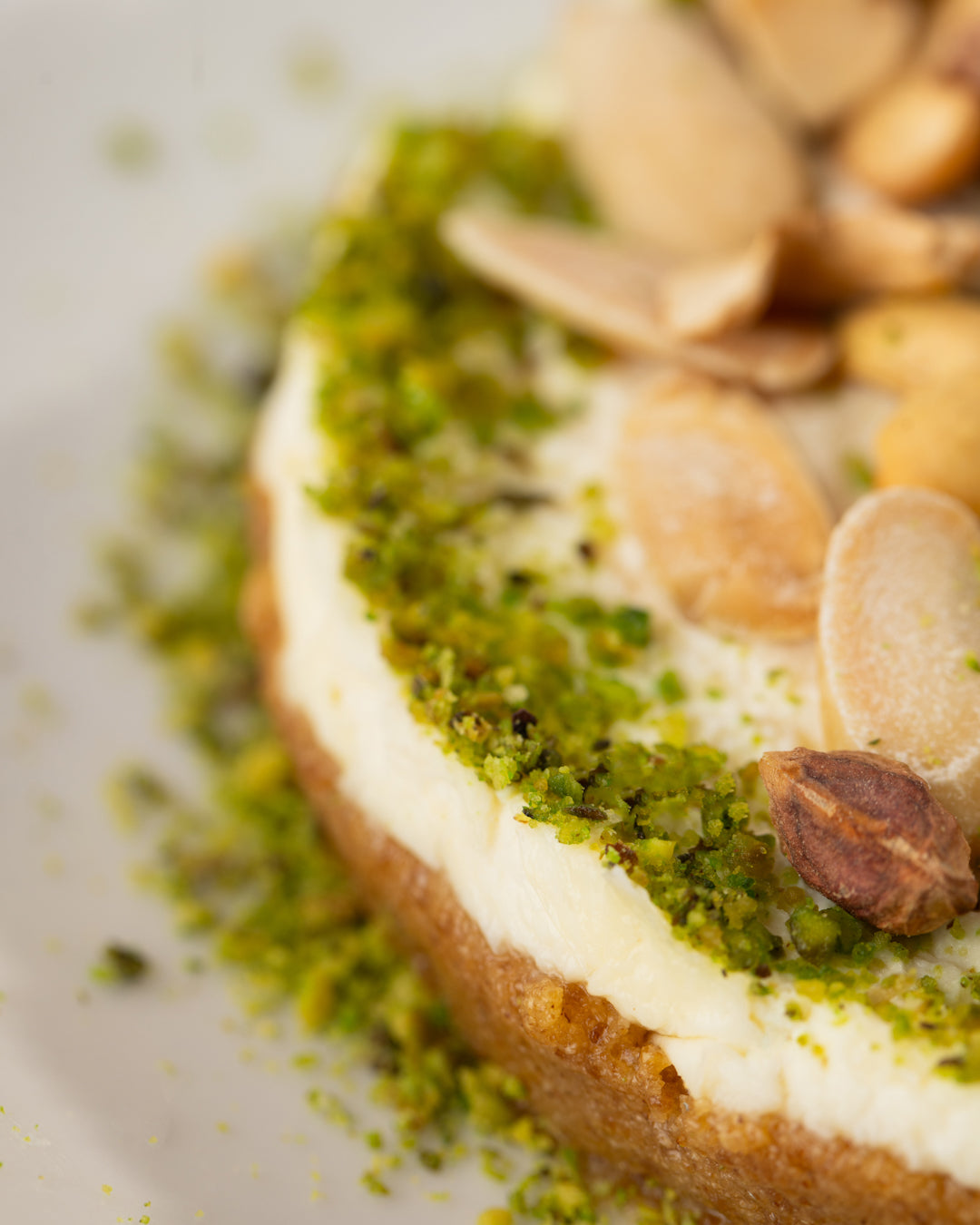 Close-up of Mafrouke Plate dessert topped with crushed pistachios, creamy kashta layer, and roasted nuts on semolina base